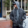 Person wearing a cny denim jacket with a hood, standing outdoors.